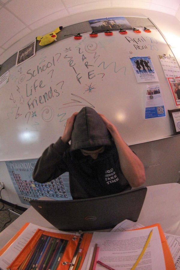 Student is pictured with a wide angle lens shaking his head. the text School, life, and friends is seen behind him on the whiteboard